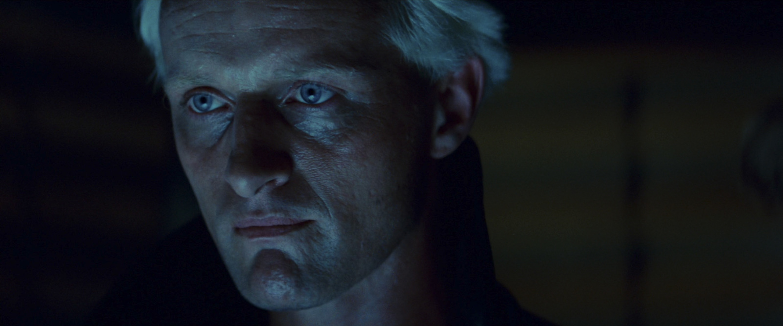 a man with white hair and blue eyes stares into the camera