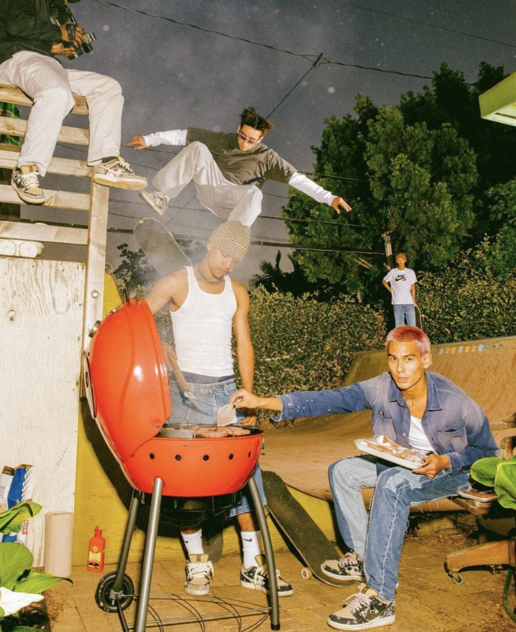 a group of young men standing around a bbq