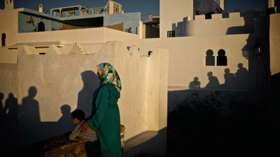 a woman in a green dress sits on a ledge in front of a white building