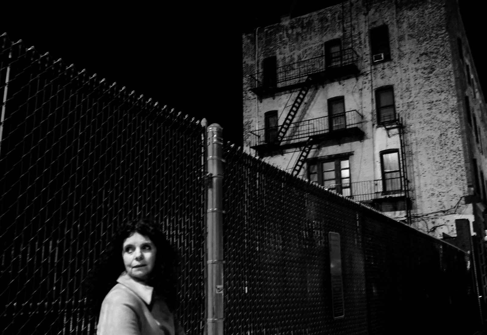 a woman standing in front of a fence at night