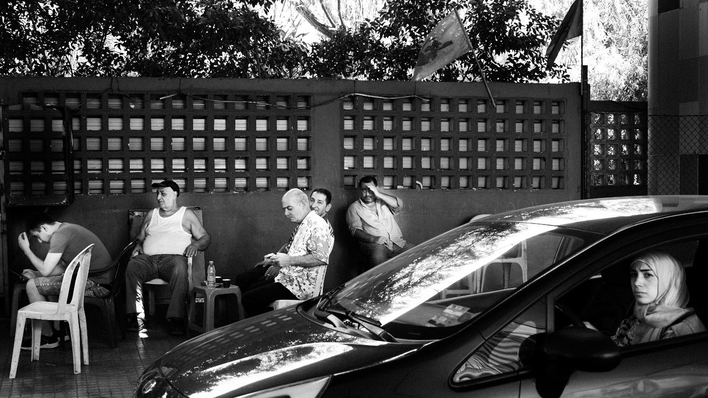 a group of people sitting at a table next to a car