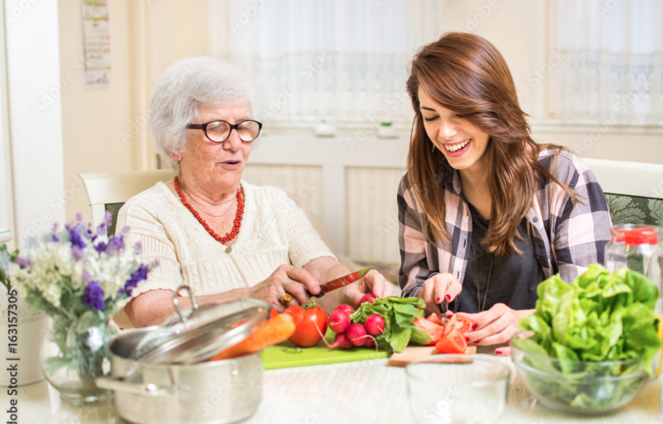 a woman is cutting vegetables with another woman