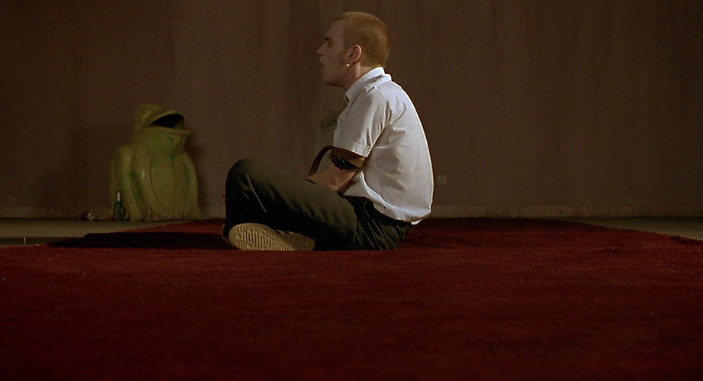 a man sitting on the floor in front of a vase