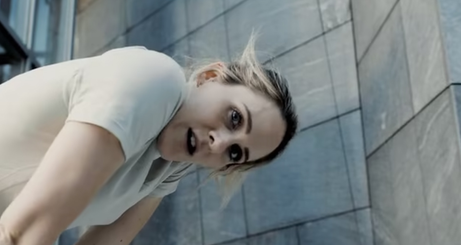 a woman in a white shirt leaning against a building