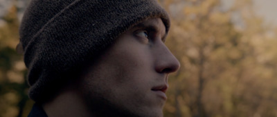 a man wearing a beanie looks off into the distance