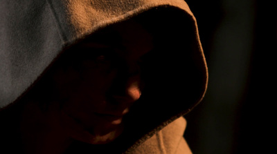 a person wearing a hooded jacket in the dark