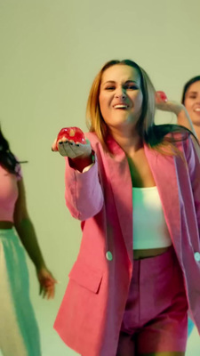 a woman in a pink jacket holding a cupcake