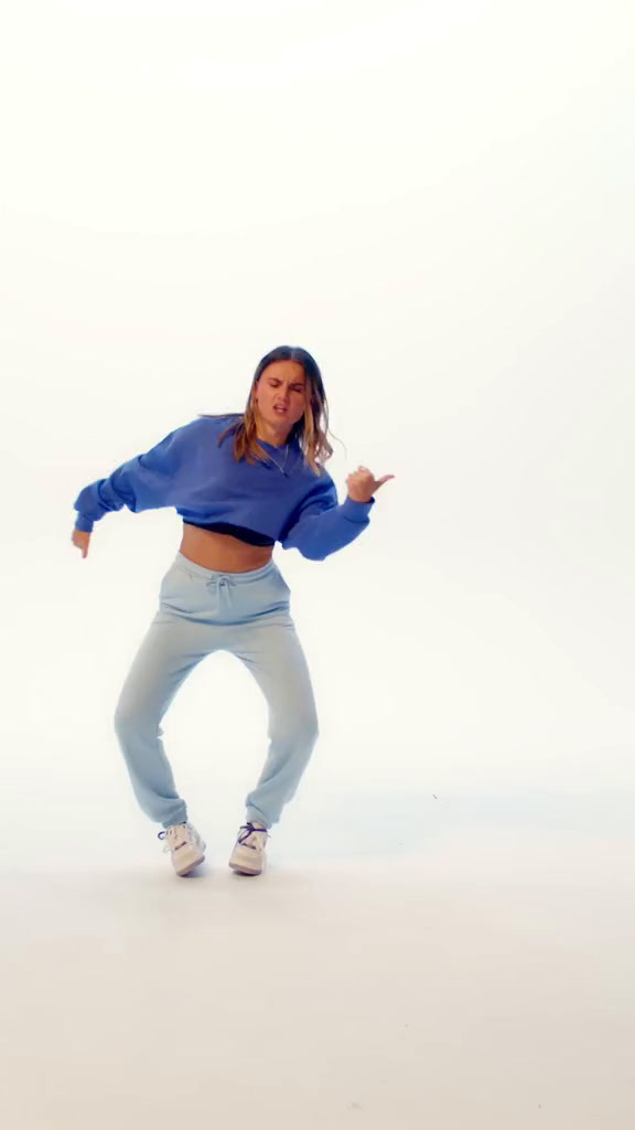 a woman in a blue sweatshirt is dancing