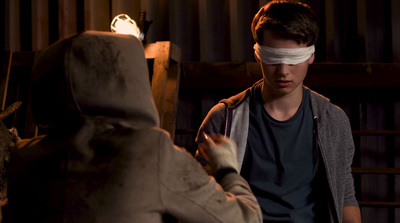 a man with a blindfold on his face standing next to a stuffed animal