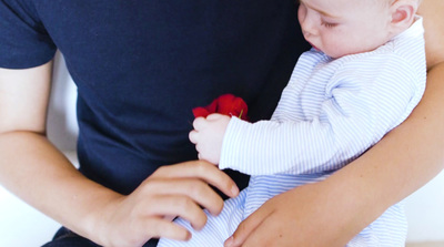 a man holding a baby who is holding a flower