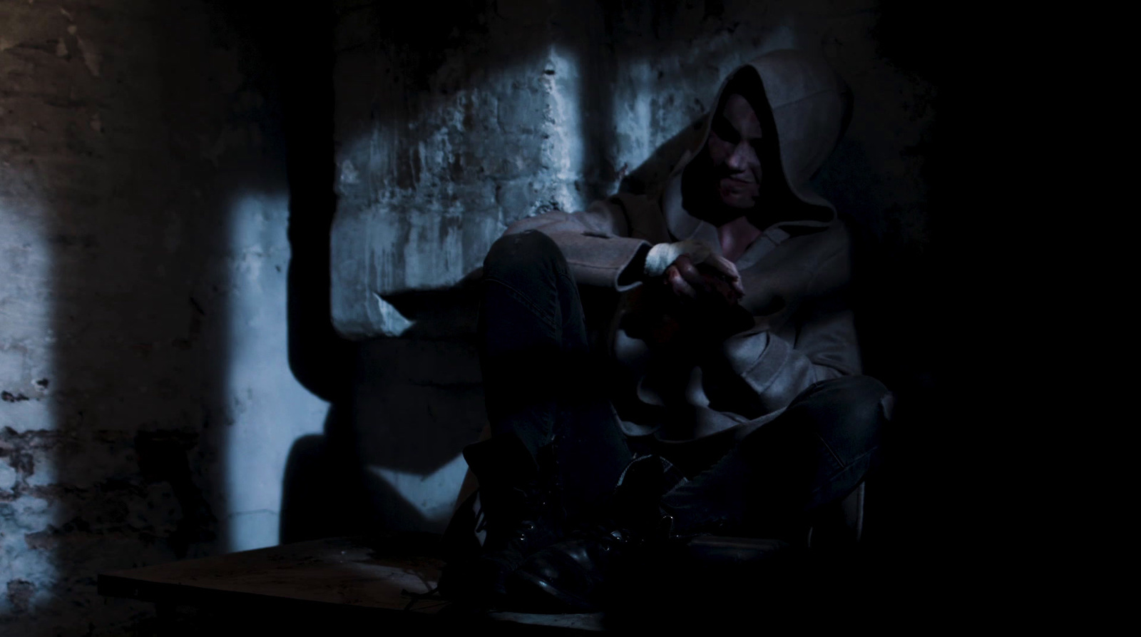 a man sitting in a dark room with a hoodie on