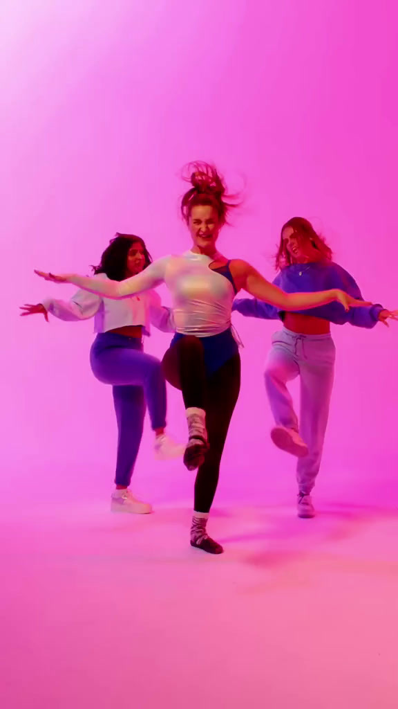 a group of young women dancing in front of a pink background