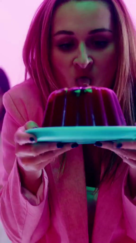 a woman in a pink shirt is looking at a chocolate cake