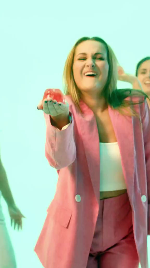 a woman in a pink suit holding a piece of fruit