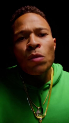 a man wearing a green hoodie and a gold necklace