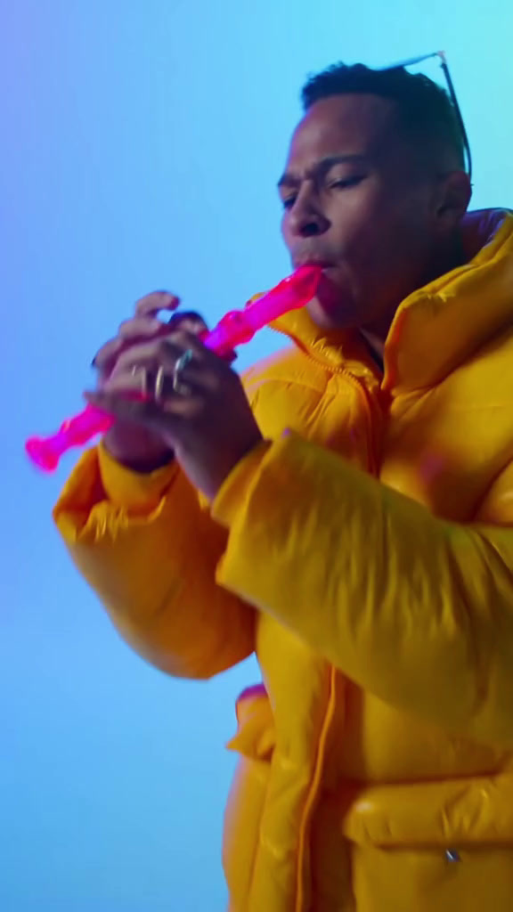 a man in a yellow jacket blowing a pink bubble