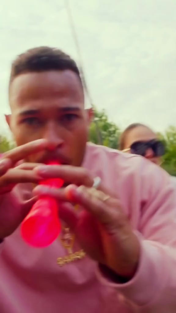 a man in a pink shirt is drinking from a red cup