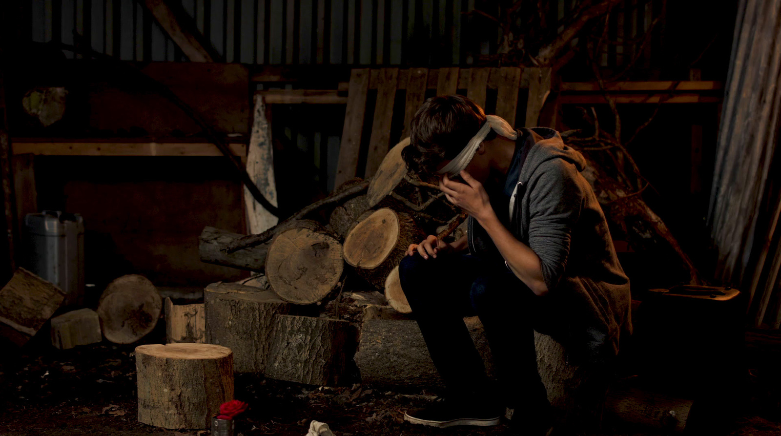 a man sitting on top of a pile of wood