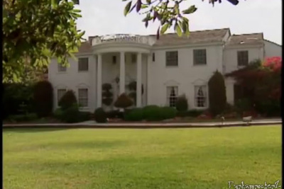 a large white house sitting on top of a lush green field