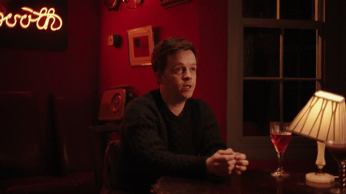 a man sitting at a table with a glass of wine