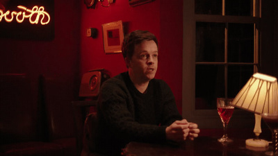 a man sitting at a table with a glass of wine