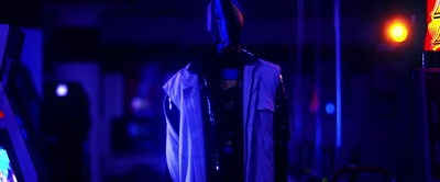 a dark room with neon lights and a costume hanging on a rack