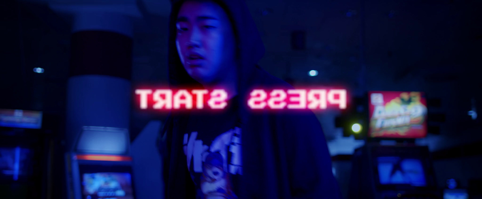 a man standing in front of a neon sign that says press start