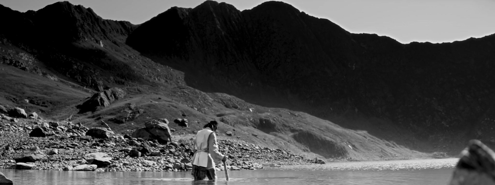 a person standing in a body of water near mountains