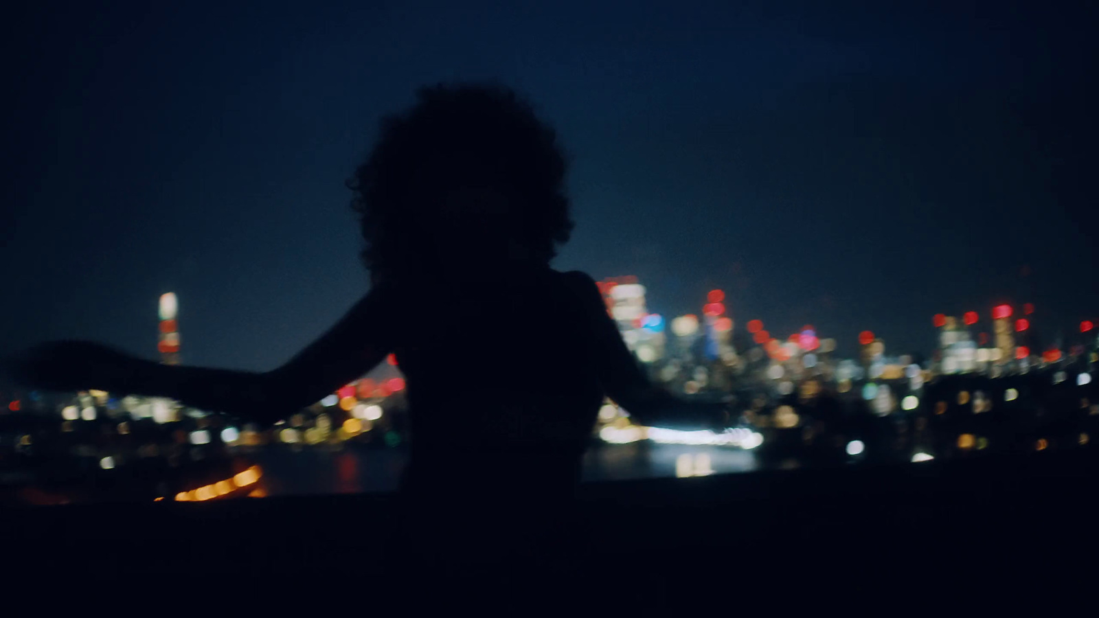 a woman standing in front of a city at night