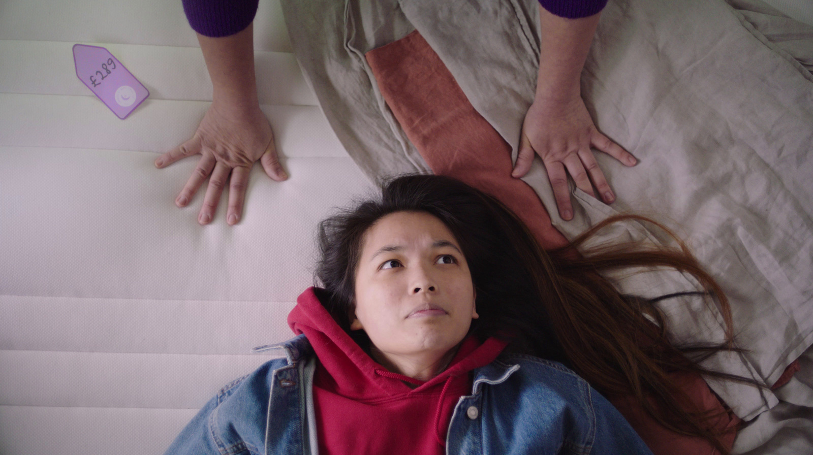 a woman laying on top of a bed next to two hands