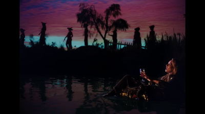 a woman sitting in the water with a glass of wine