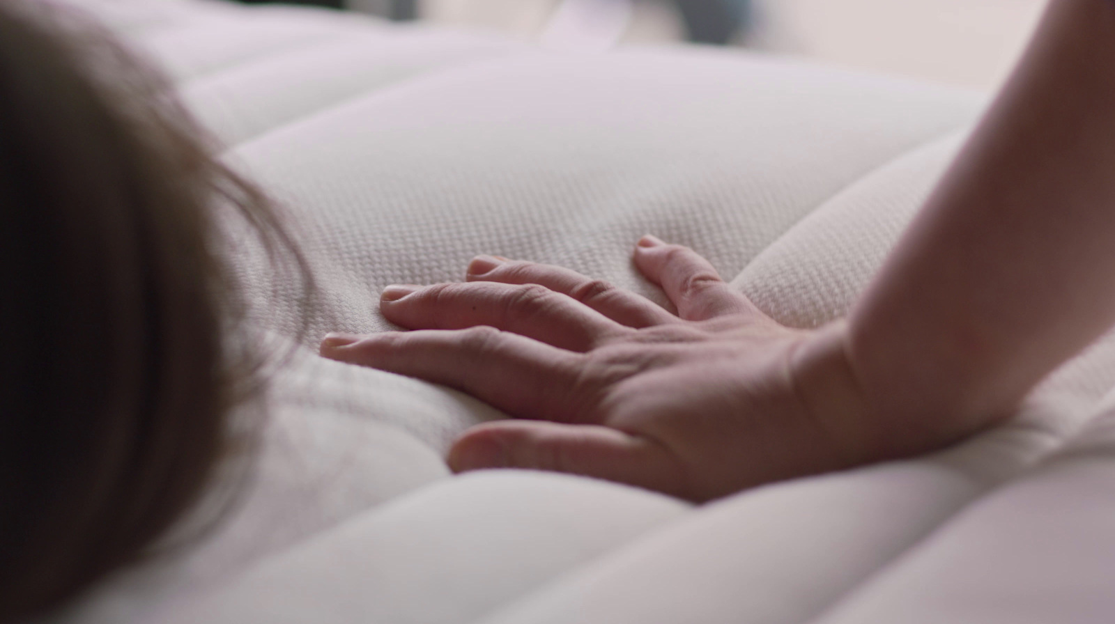 a person holding a baby's hand on a bed