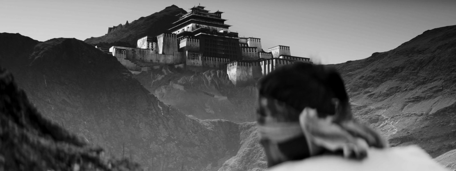 a man standing on top of a mountain next to a tall building