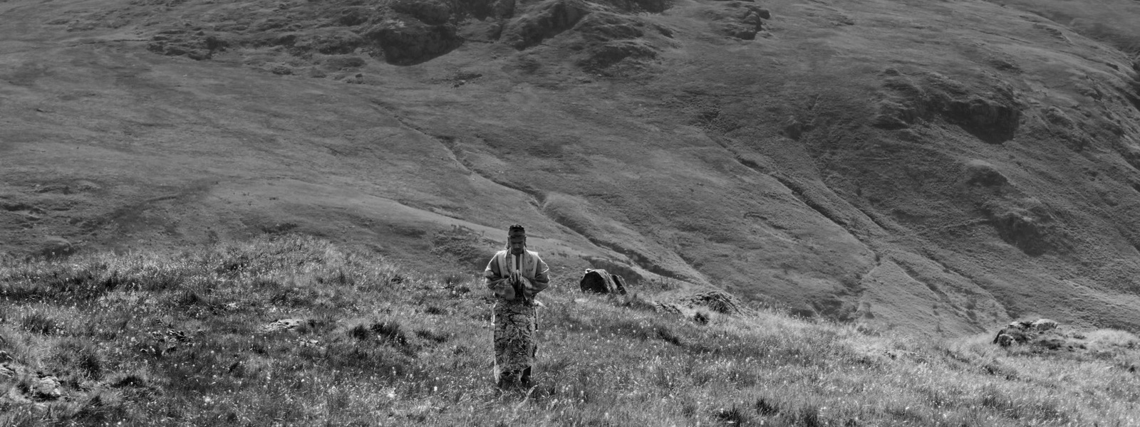 a man standing on top of a grass covered hillside