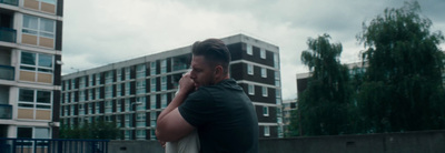 a man standing in front of a building talking on a cell phone