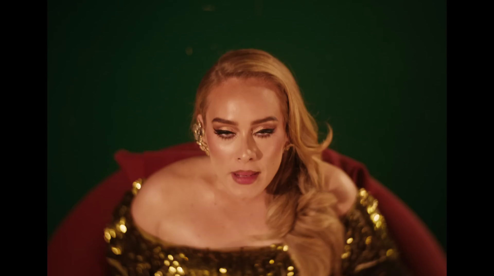 a woman in a gold dress sitting in a red chair