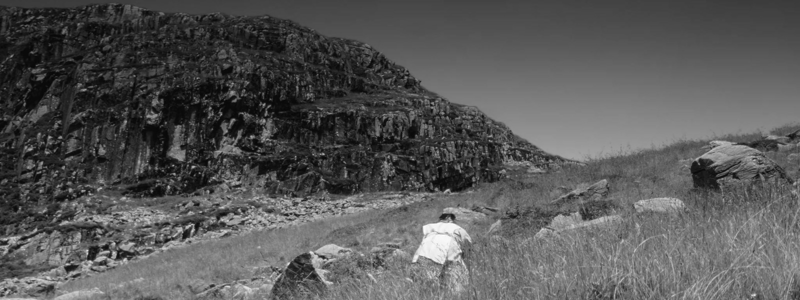 a black and white photo of a person walking up a hill