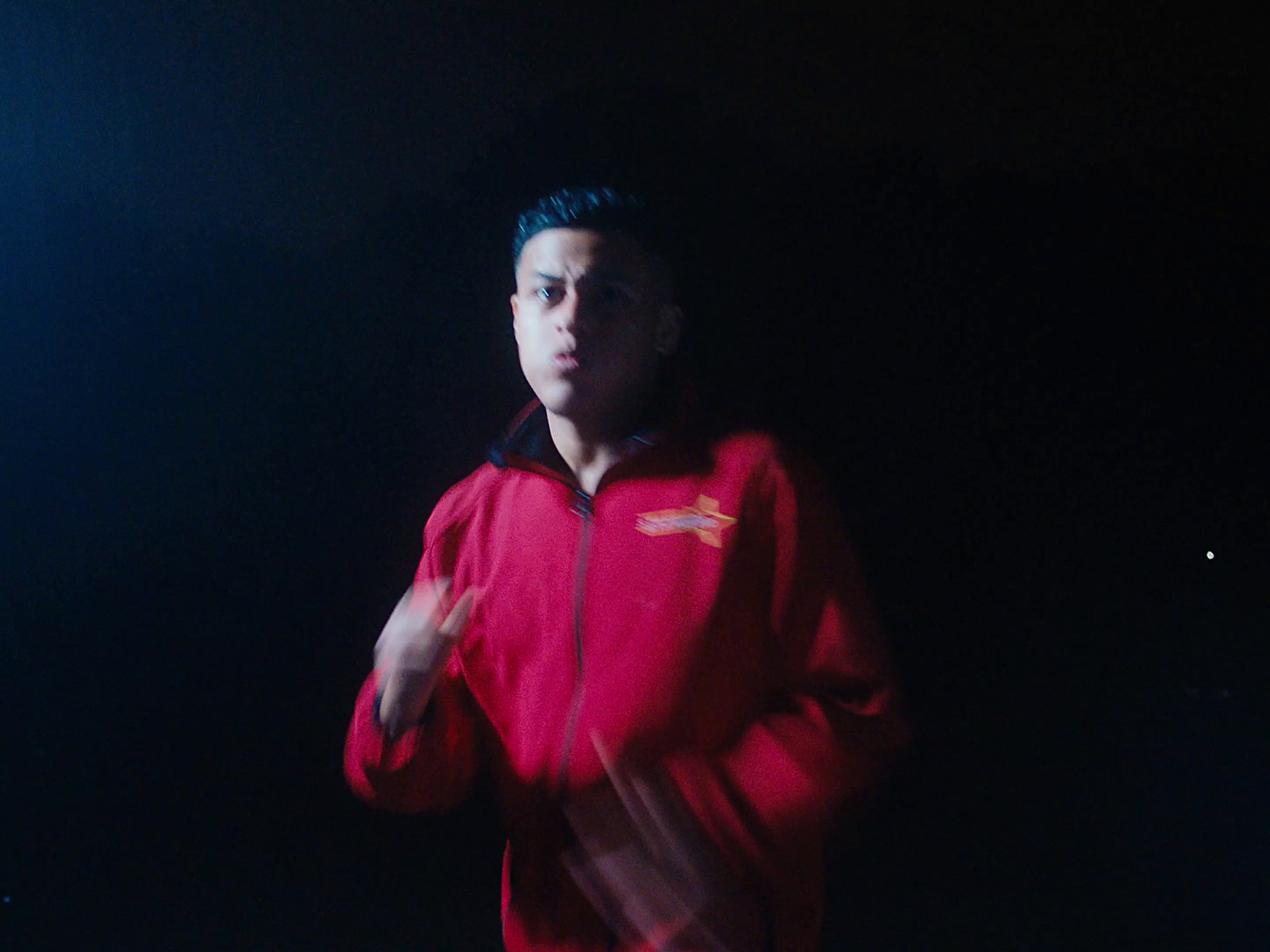 a man in a red jacket standing in the dark