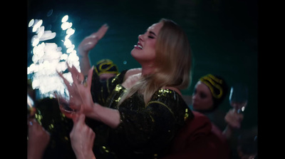 a woman in a black and gold dress is holding her hands up