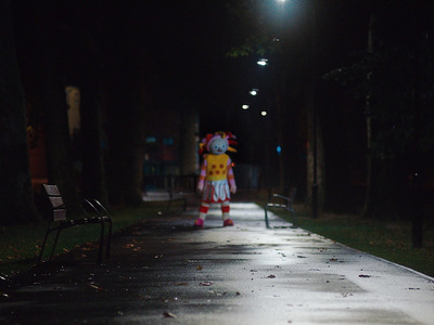 a person dressed as a clown walking down a street at night