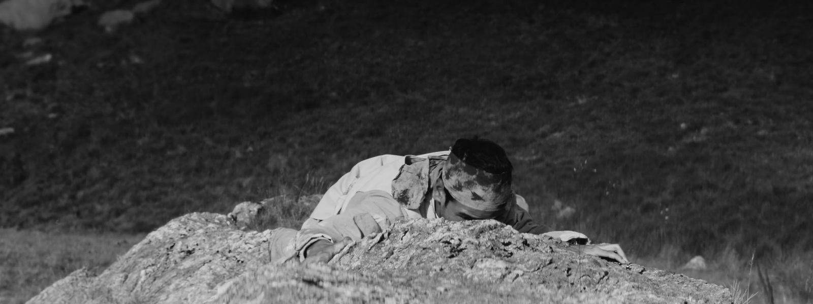 a black and white photo of a person laying on a rock