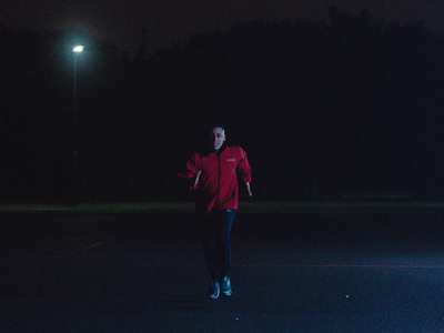 a man in a red jacket throwing a frisbee at night