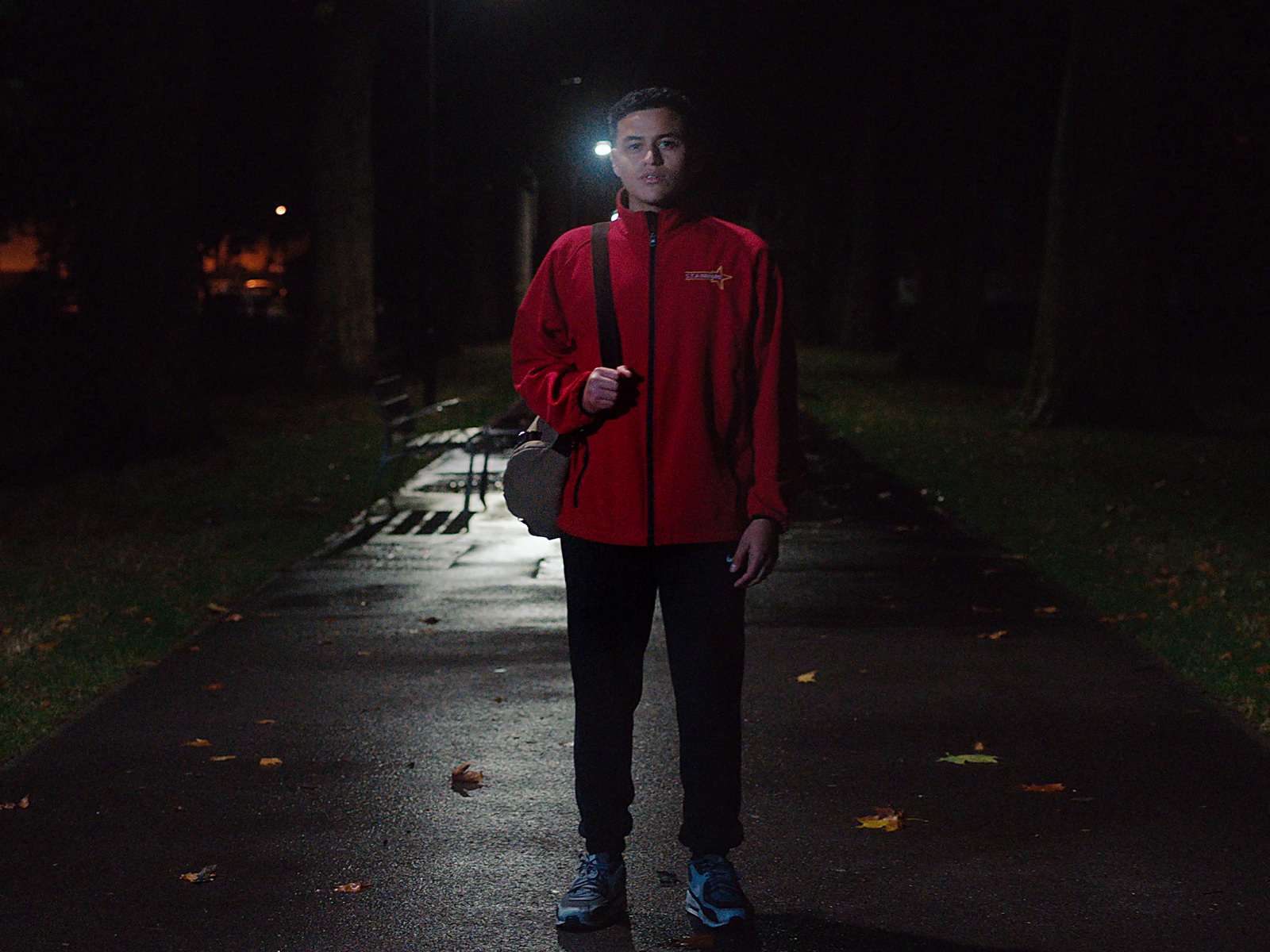 a man in a red jacket is standing in the dark