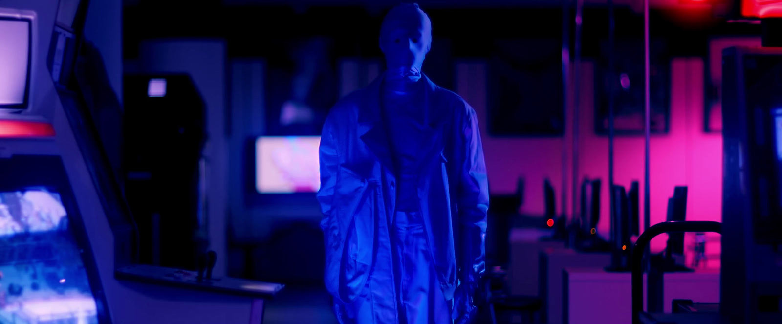 a man in a blue raincoat standing in a dark room