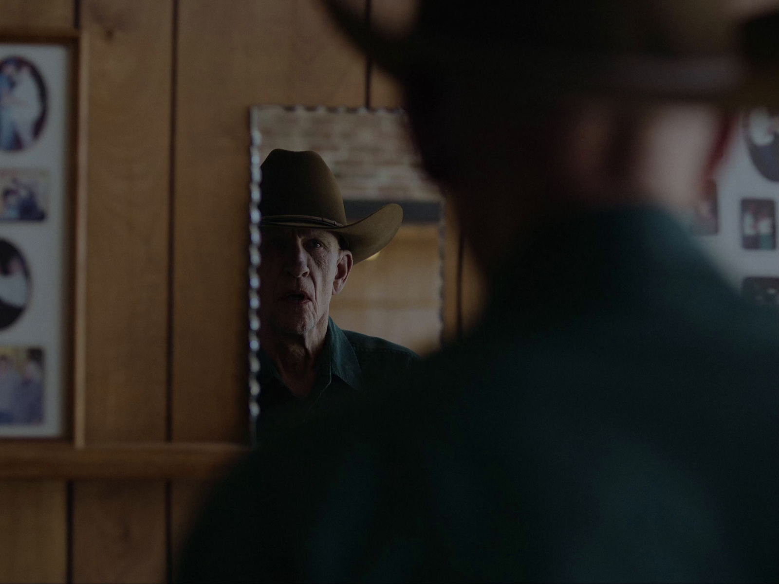 a man in a cowboy hat looking at himself in a mirror