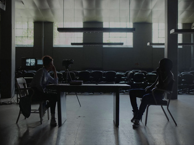 two people sitting at a table in an empty room