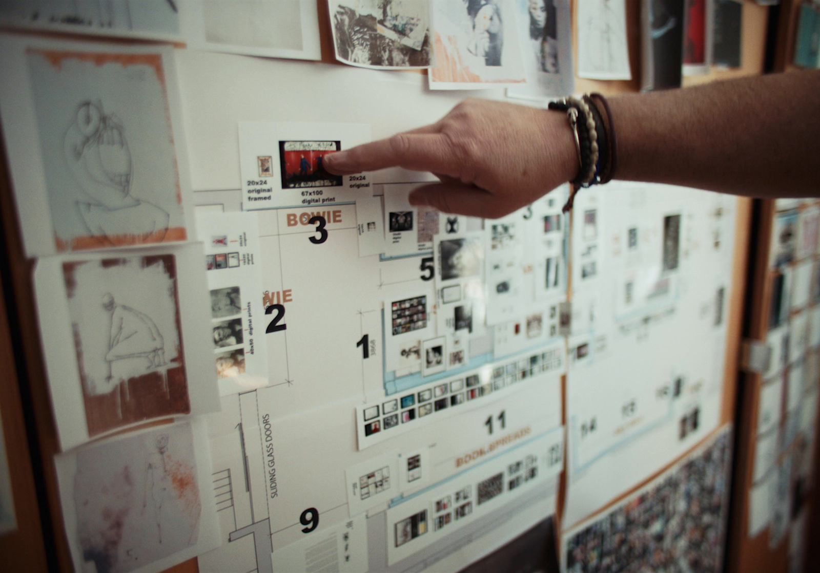 a person's hand pointing at a calendar on a wall