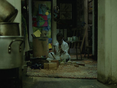 a man sitting on the floor working on a piece of wood