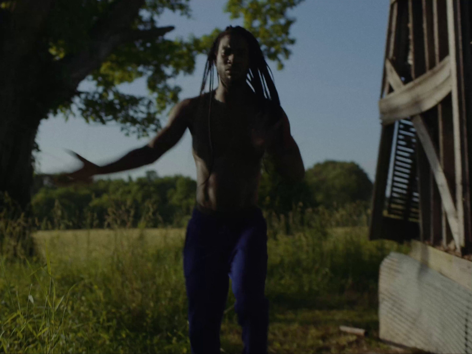 a man with dreadlocks running through a field