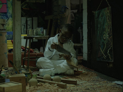 a man sitting on the floor working on a piece of wood